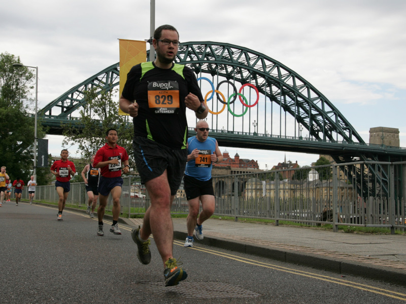 Man in glasses running in front of the Tyne Bridge